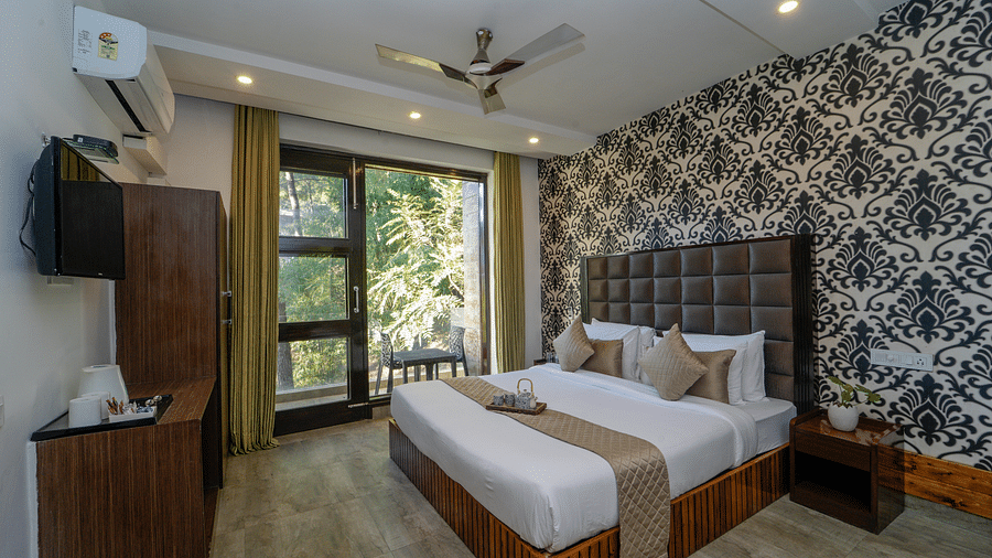 The deluxe room at DLS Whispering Winds featuring a bed, bed side tables, flat screen TV, other room amenities and a glass door leading to the balcony